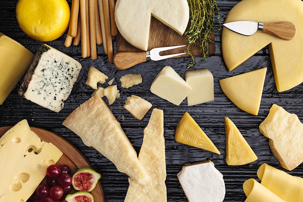 Top View Of A Dark Table Filled With A Wide Variety Of Wisconsin Cheeses.